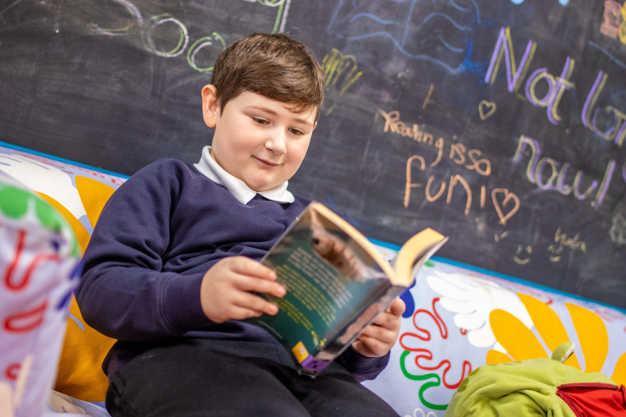 Boy reads book in school library.