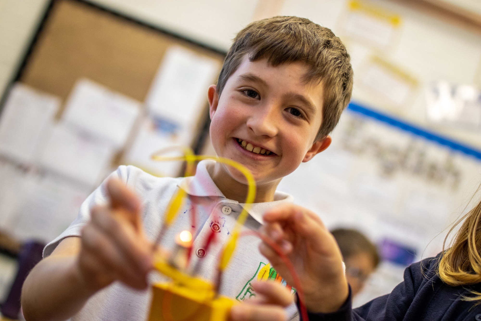 A boy uses wires to light a lightbulb.