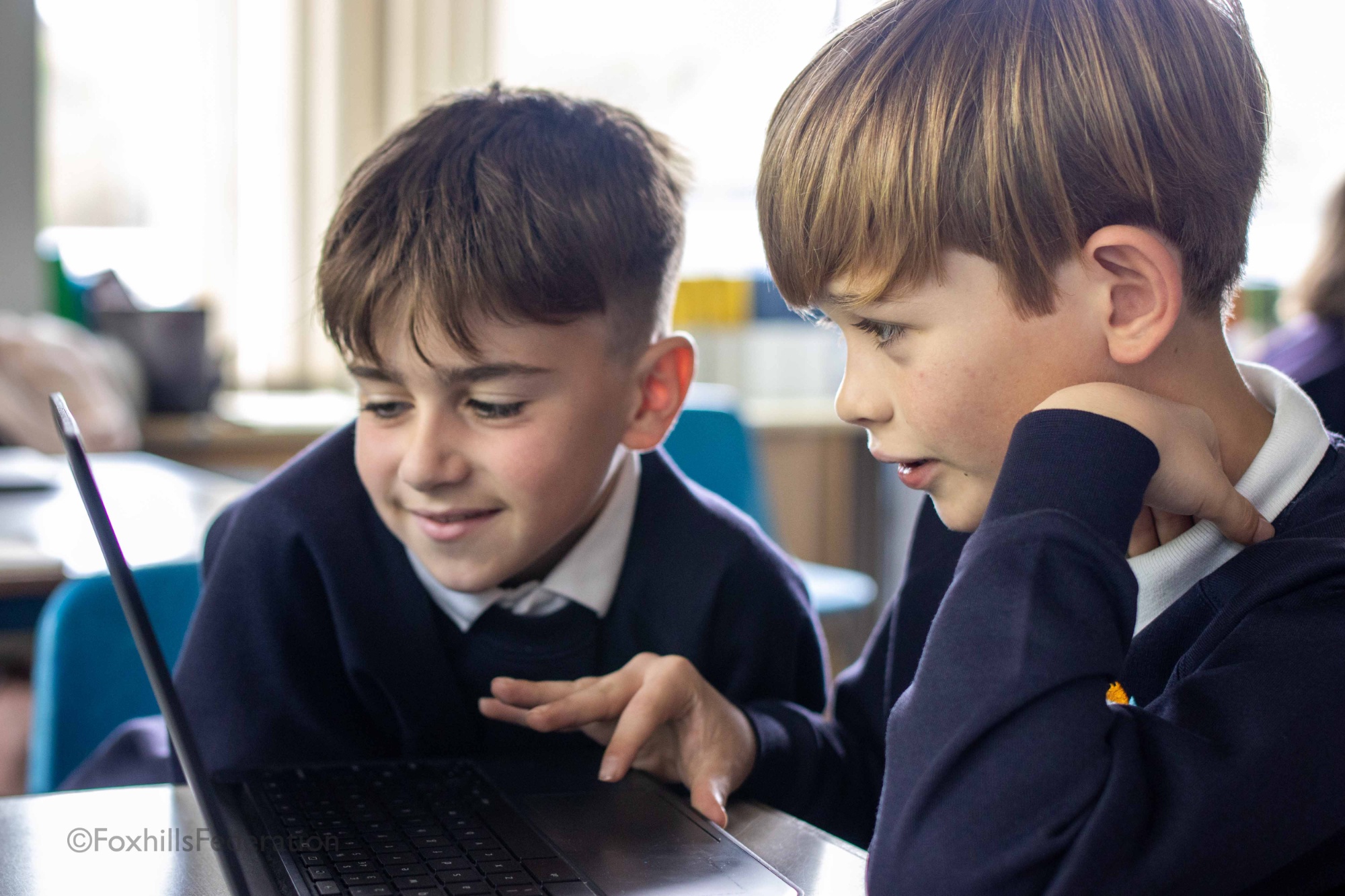 Two boys scroll through a spreadsheet