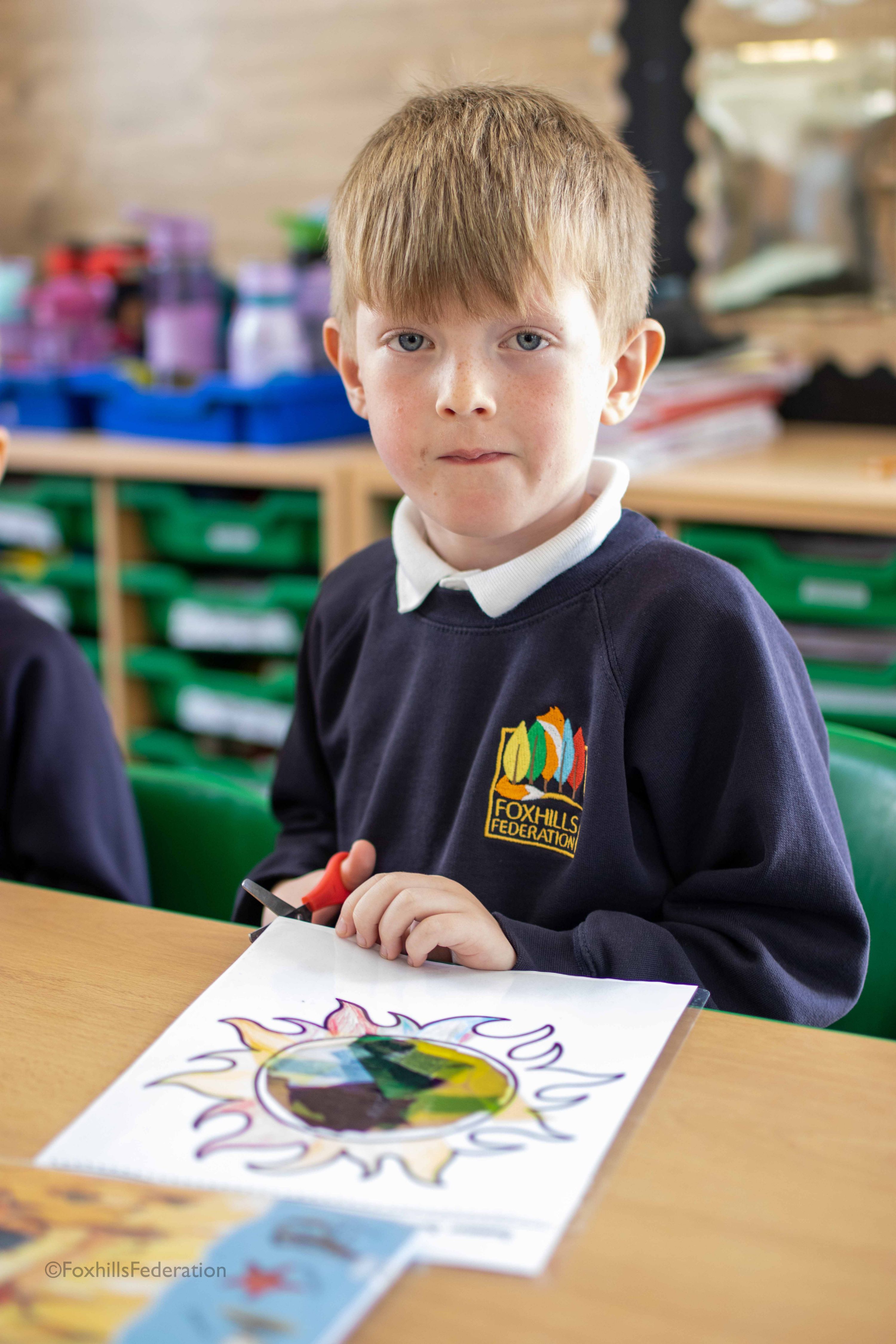 A boy smiles while cutting out colourful foil