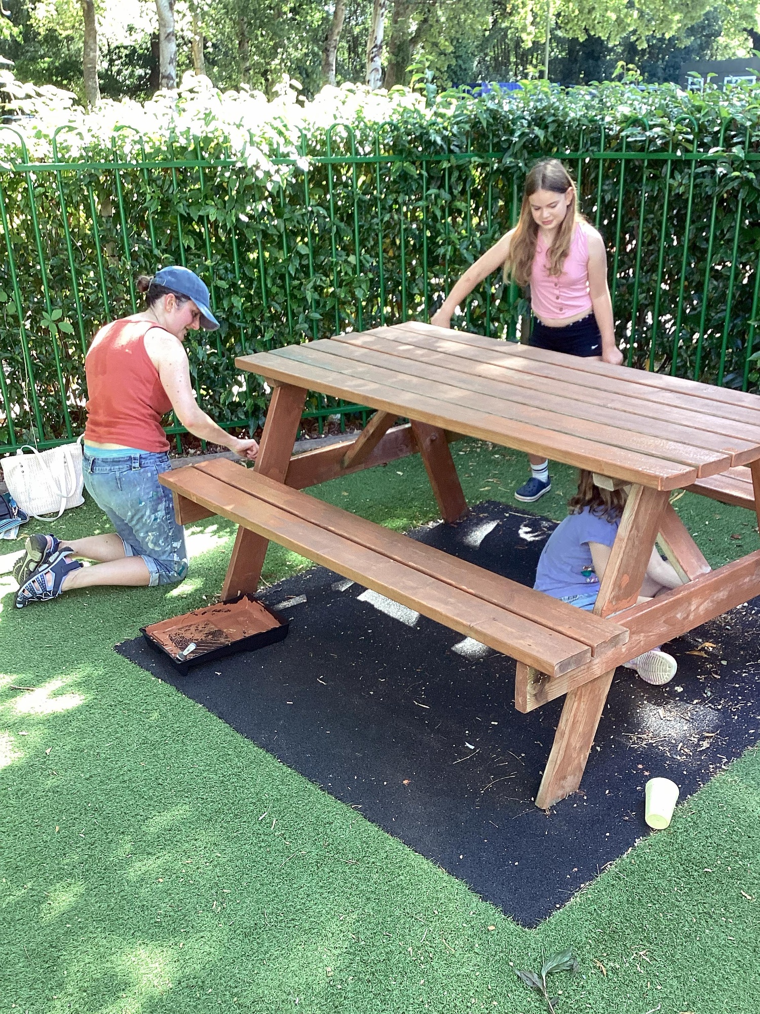 A parent and children paint a bench