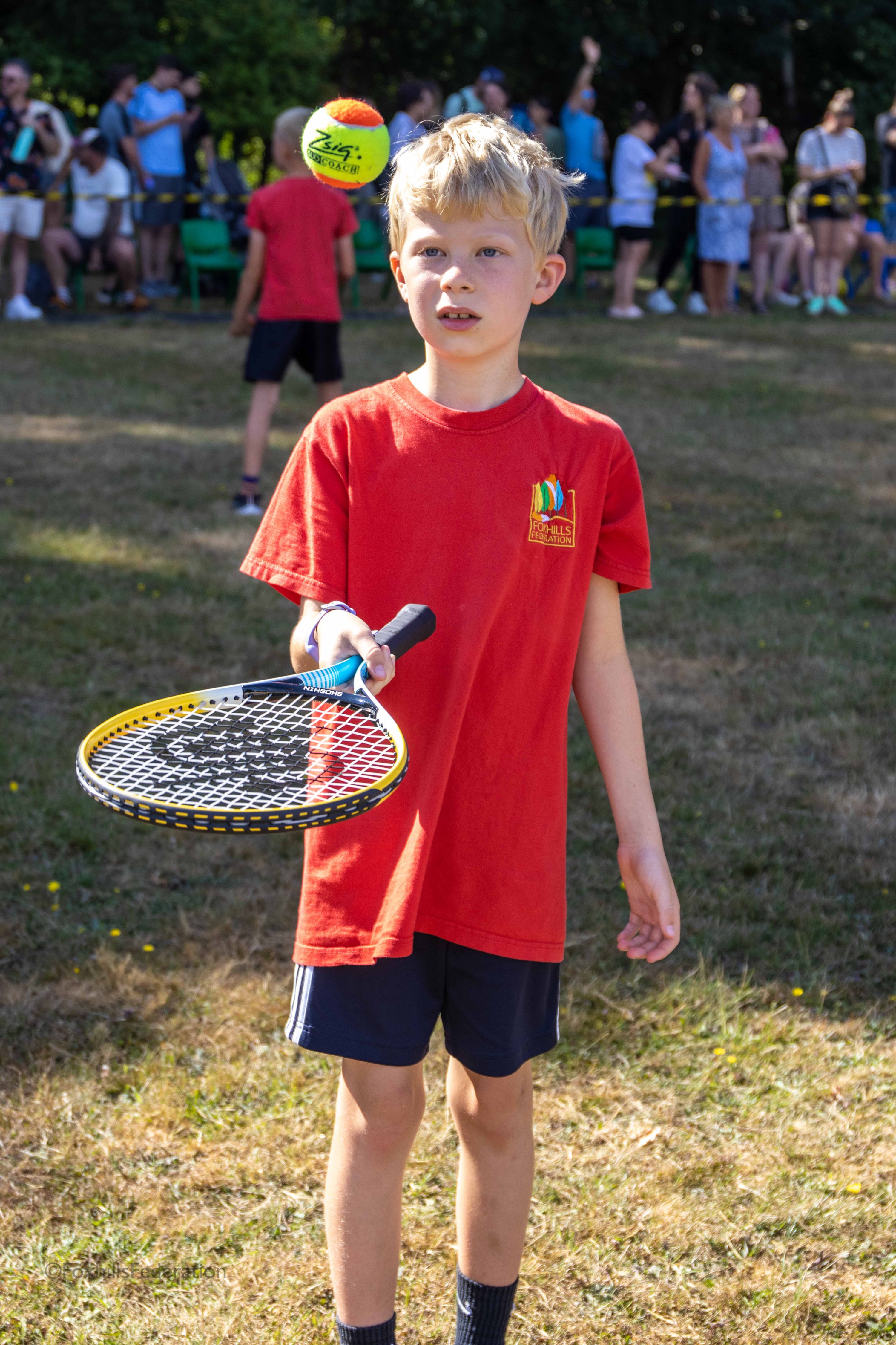 A boy tries to catch a ball on a tennis racket