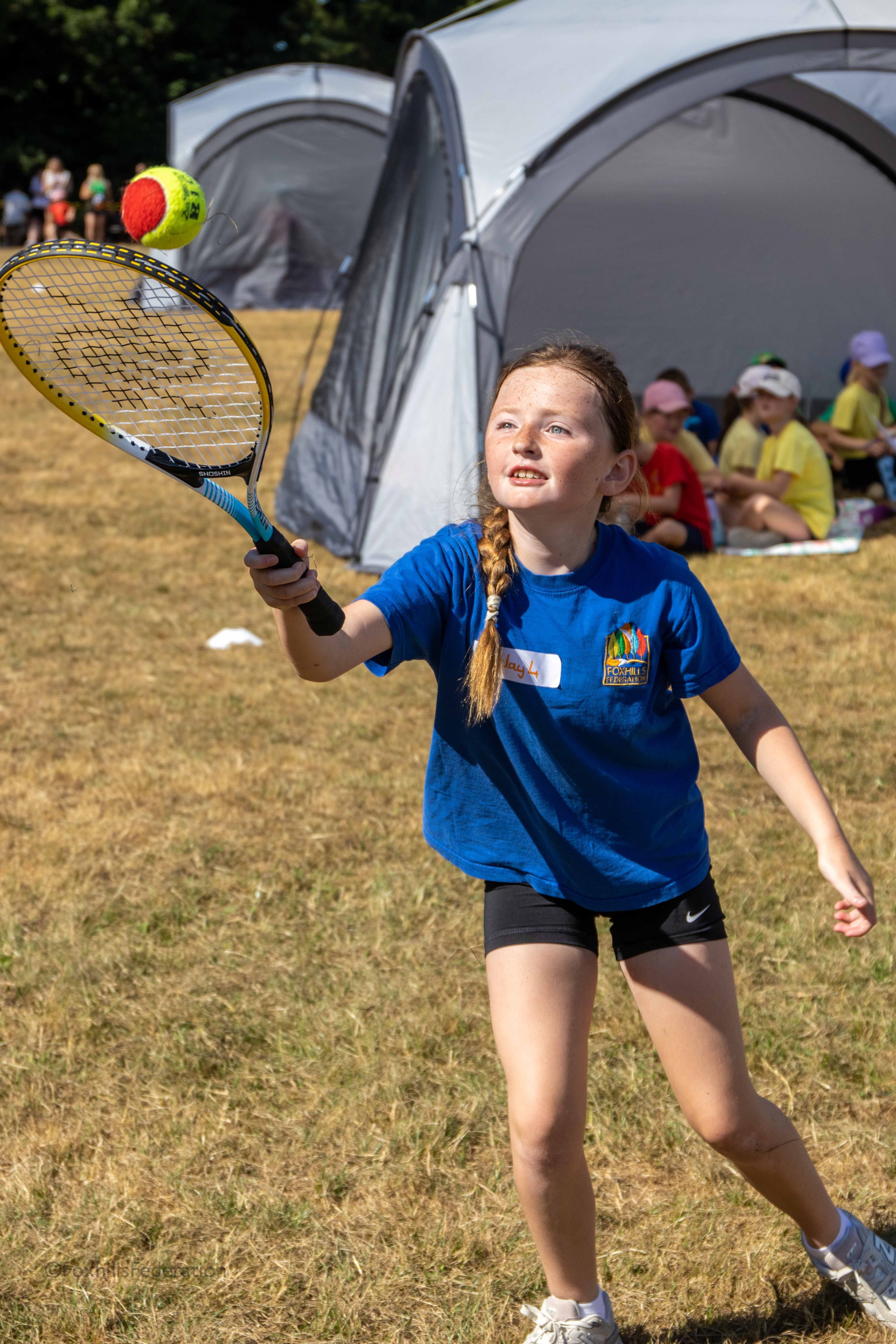 A girl tries to catch a ball on a tennis racket