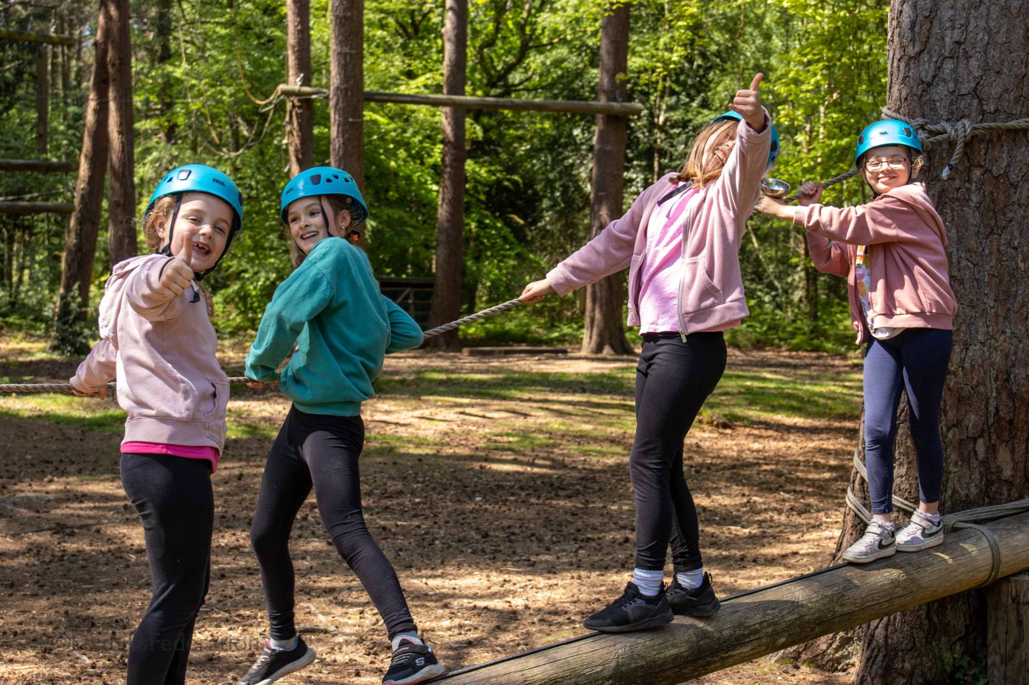 A group of girls pose on a wooden beam