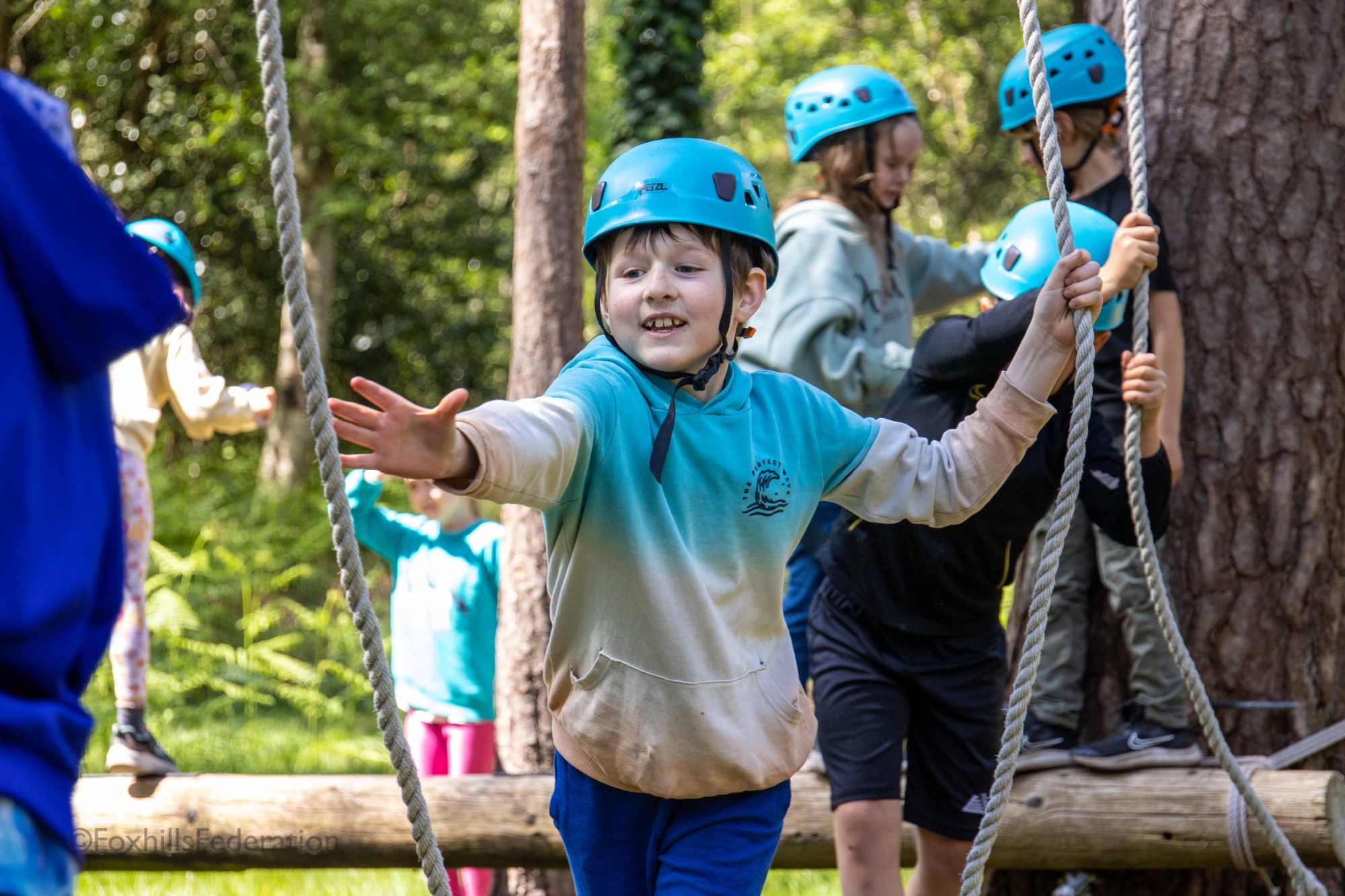 A boy walks across a low rope course