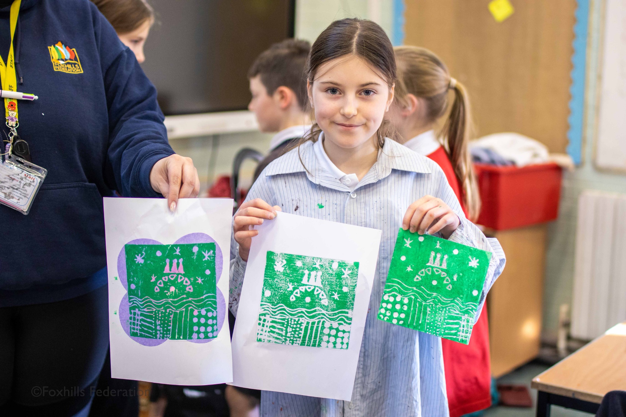 A girl holds up work created by stamp printing.