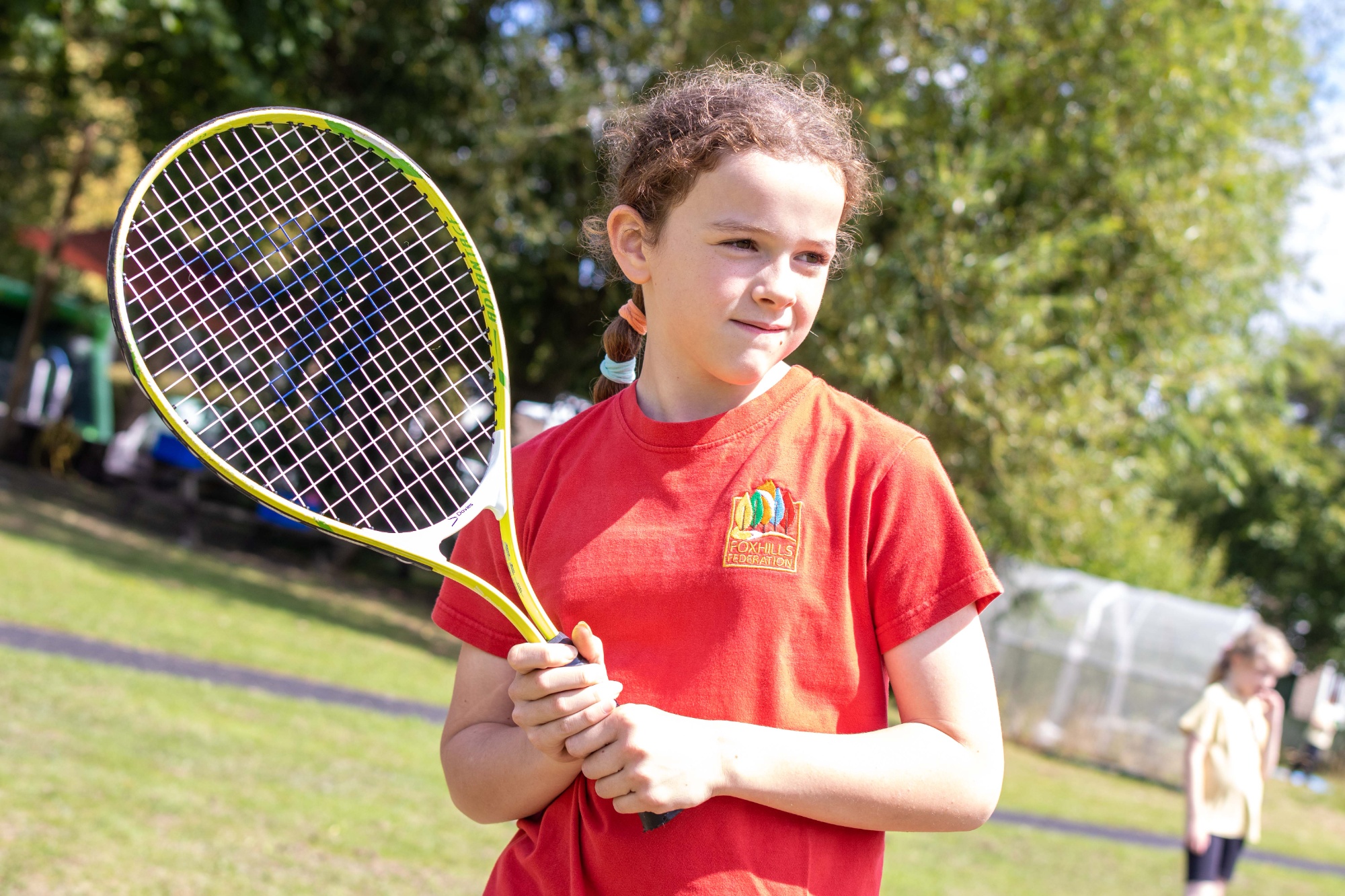 A girl holds a tennis racket waiting for a ball to be thrown.