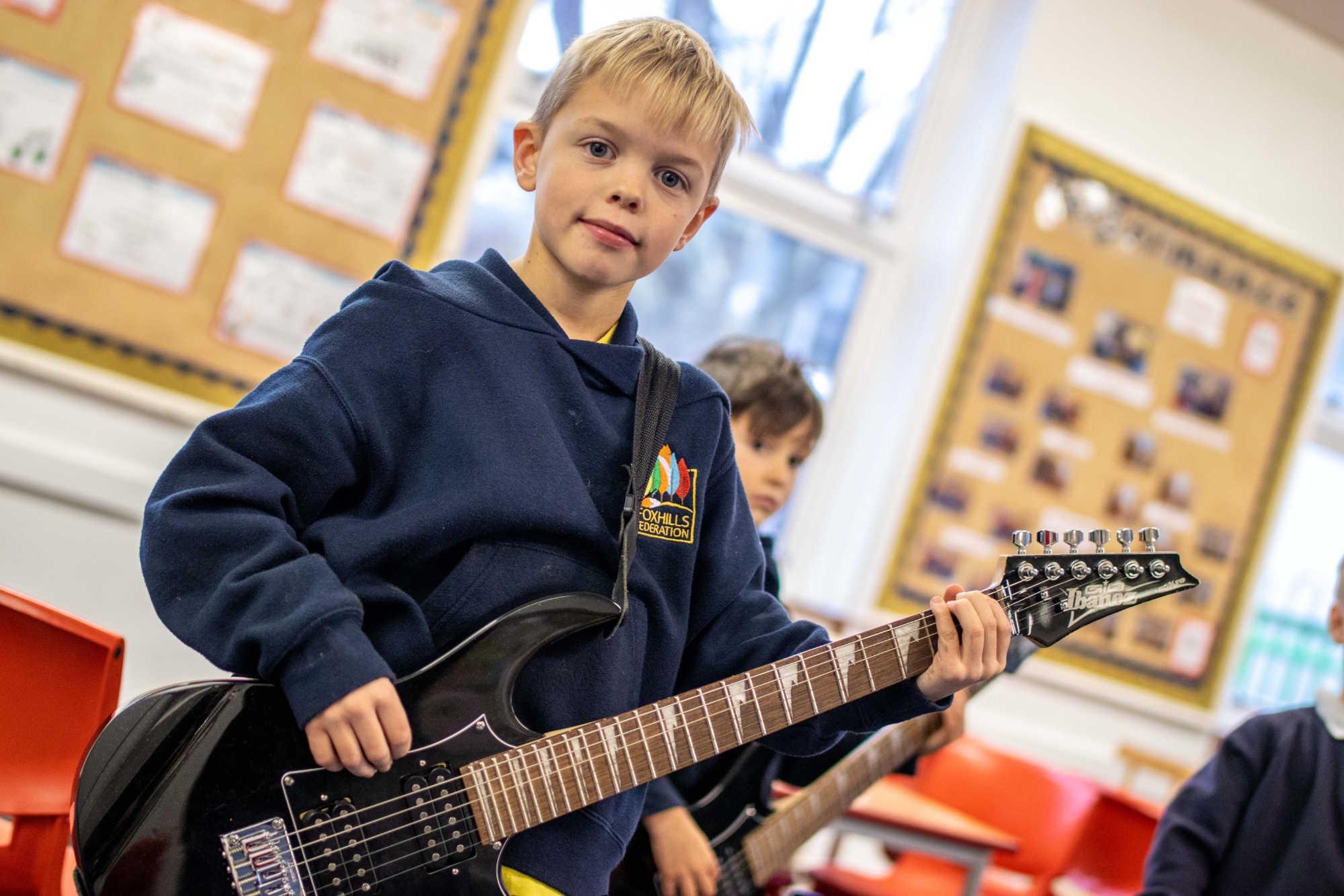 A Junior School aged boy practices playing the electric guitar.