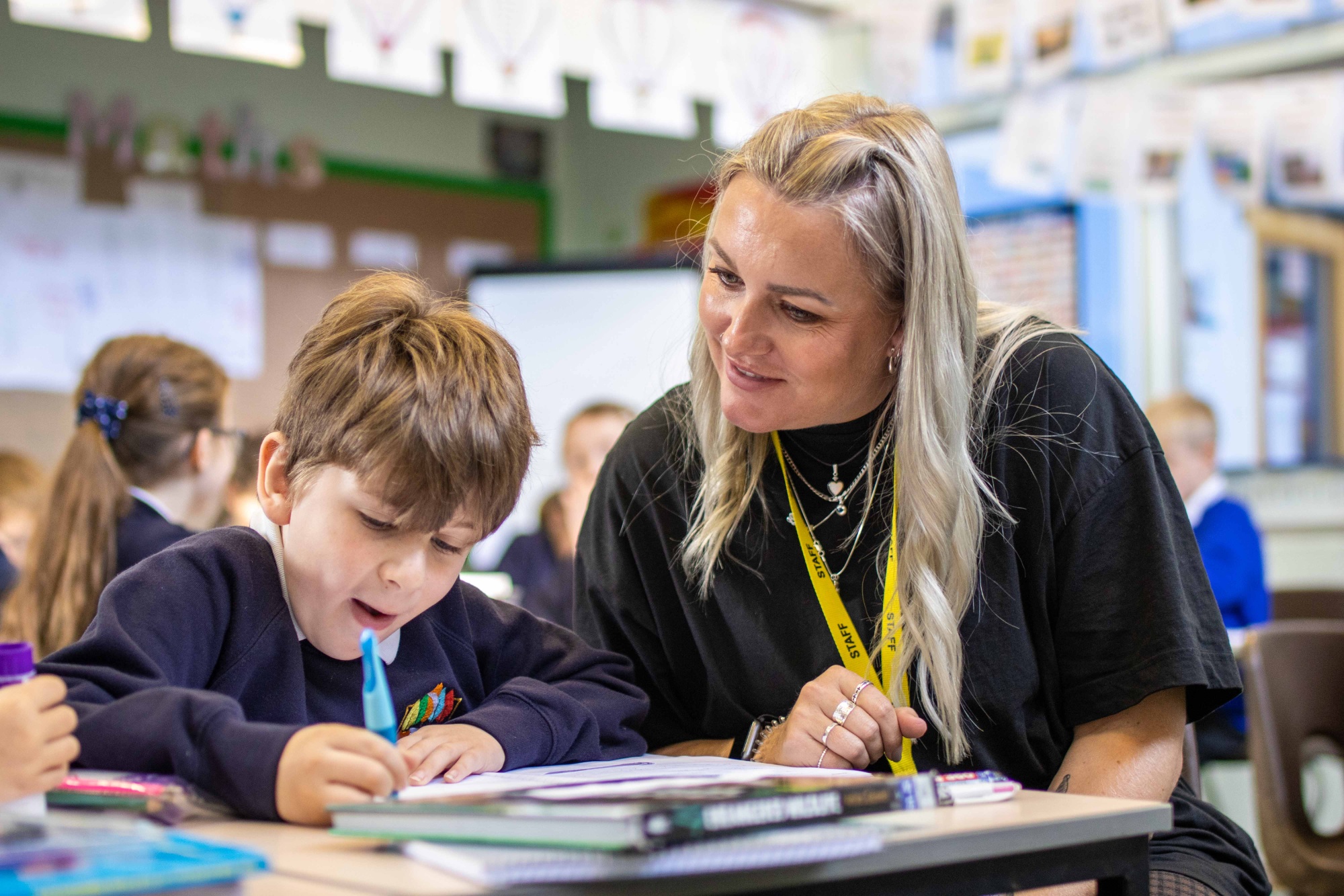 A teaching assistant helps a boy with his school work.