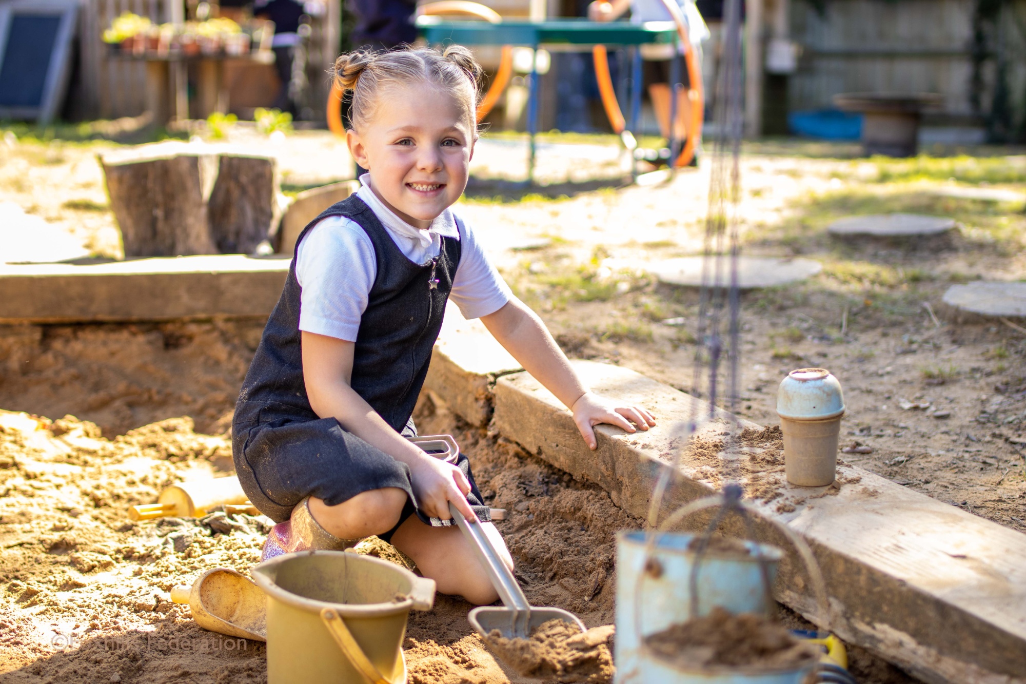 A young girl from Reception plays in a sand box.